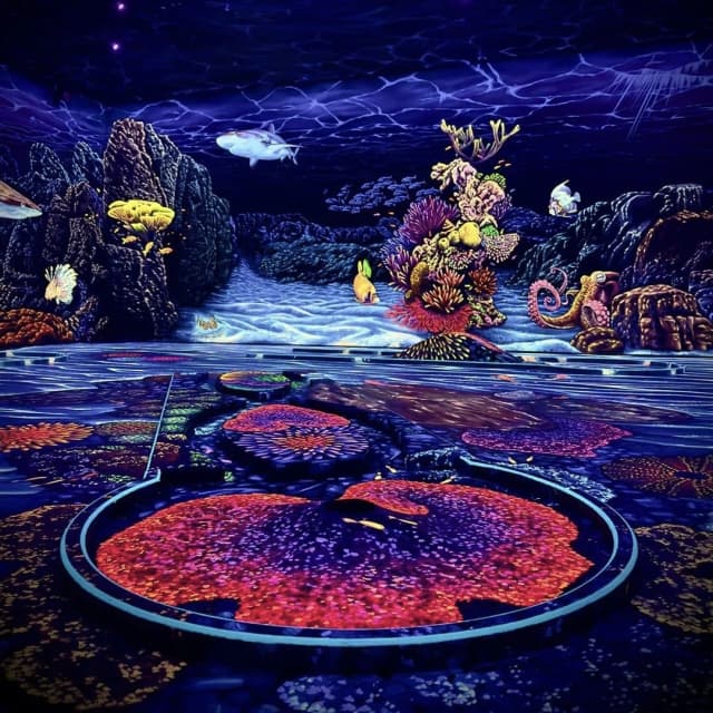 Schwarzlicht-Minigolf in Dresden mit leuchtenden Korallen, Fischen und einer intensiv blau-violetten Unterwasserlandschaft